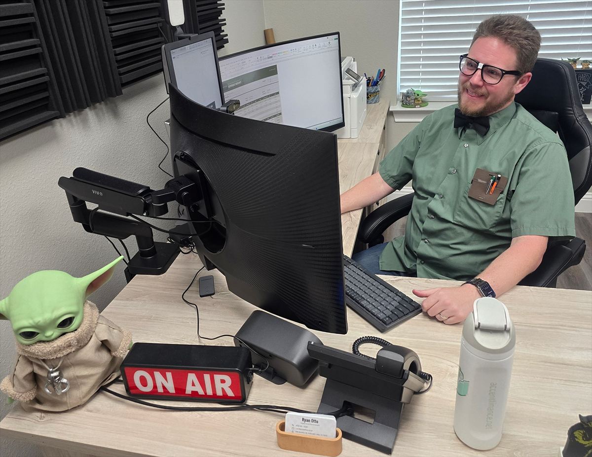 Ryan Otto at his desk with the ON AIR sign lit